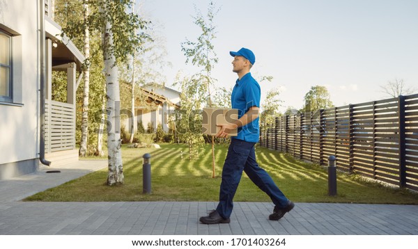 Delivery Man Holding Card Board Package Enters\
Through the Gates and Walks to the House and Knocks. Delivering\
Postal Parcel. In the Background Beautiful Suburban Neighbourhood.\
Side View
