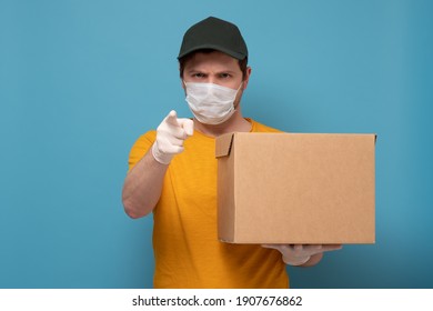 Delivery man holding cardboard box in medical rubber gloves and mask. Online shopping and Express delivery on quarantine - Shutterstock ID 1907676862