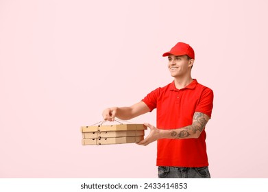 Delivery man holding cardboard boxes with tasty pizza on pink background - Powered by Shutterstock