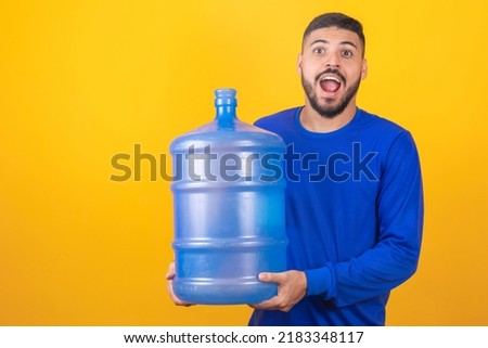 Delivery man holding empty water bottle on yellow background with free space for text.