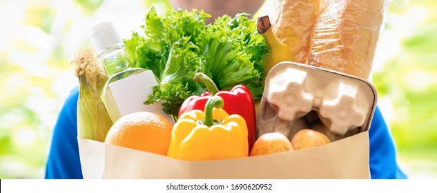 Delivery man holding a grocery bag ready to deliver to the customer at home - Powered by Shutterstock