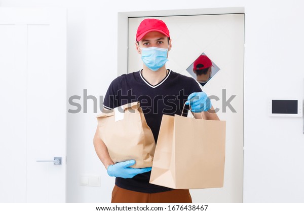 Delivery man\
holding paper bag with food on white background, food delivery man\
in protective mask and protective\
gloves