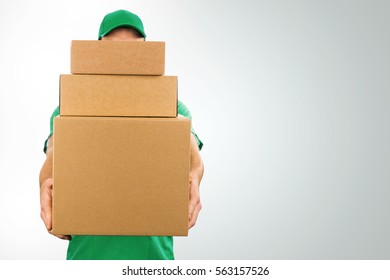 delivery man holding pile of cardboard boxes in front with copy space