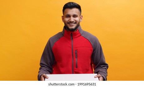 Delivery man holding a pizza box in his hand. Dressed in red uniform smiling. Concept of home delivery service. Yellow background studio shot. Isolated Man. 