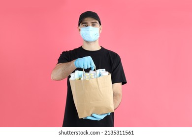 Delivery man holds bag with medicines on pink background - Shutterstock ID 2135311561