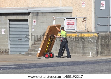 Delivery man making a delivery to a back dock of a shop with a hand truck