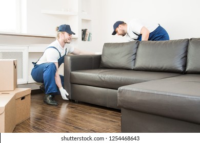 Delivery Man Move Furniture Carry Sofa For Moving To An Apartment. Professional Worker Of Transportation, Male Loaders In Overalls