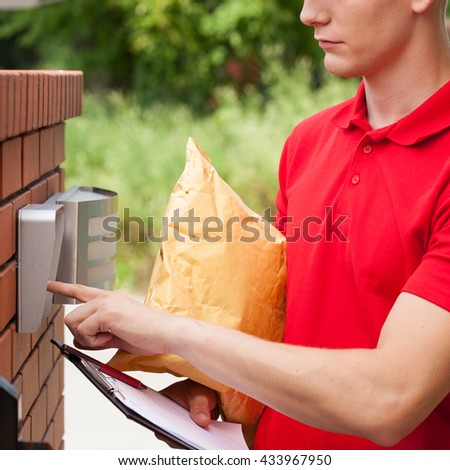 Delivery man with parcel calling client on entryphone