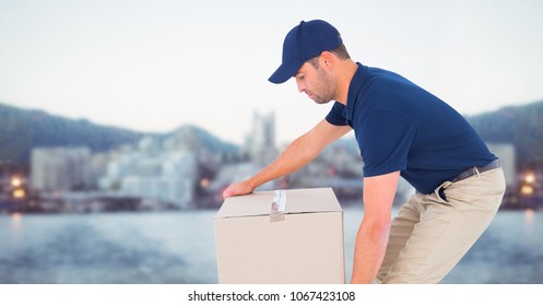 Delivery Man Picking Up Box Against Blurry Skyline