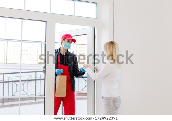 delivery man in protective\
mask and medical gloves holding a paper box. Delivery service under\
quarantine, disease outbreak, coronavirus covid-19 pandemic\
conditions.