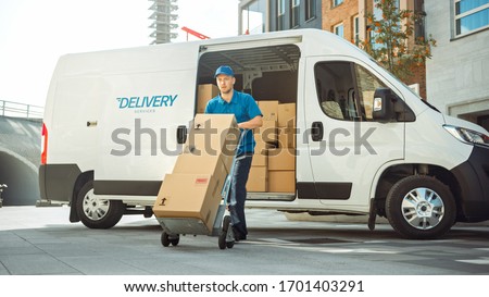 Delivery Man Pushes Hand Truck Trolley Full of Cardboard Boxes Hands Package to a Customer. Courier Delivers Parcel to Man in Business District.