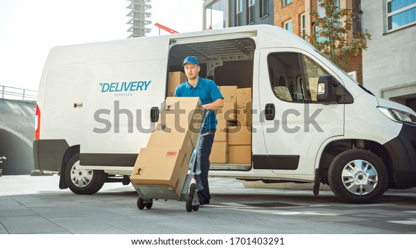 Delivery Man Pushes Hand Truck Trolley Full of\
Cardboard Boxes Hands Package to a Customer. Courier Delivers\
Parcel to Man in Business\
District.