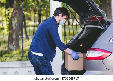 Delivery Man Putting A Box  With Food In The Car, Food Delivery Man In Protective Mask