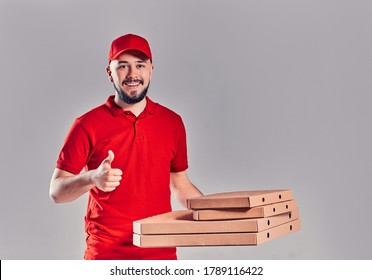 Delivery man in red cap, t-shirt giving food order pizza boxes isolated on gray background. Male employee pizzaman courier holding pizza in empty blank cardboard flatbox copy space. Service concept - Shutterstock ID 1789116422