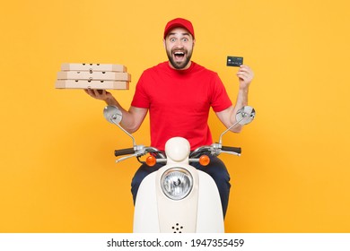 Delivery Man Red Cap T-shirt Uniform Driving Moped Motorbike Scooter Hold Pizza In Cardboard Bank Card Isolated On Yellow Background Studio Fun Guy Employee Working Courier Service Quarantine Concept.
