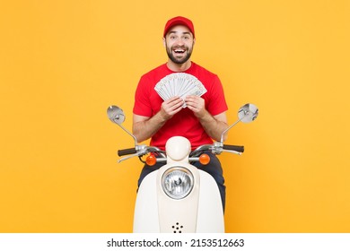 Delivery man in red cap t-shirt uniform driving moped motorbike scooter hold cash money isolated on yellow background studio Guy employee working courier Service quarantine pandemic covid-19 concept.