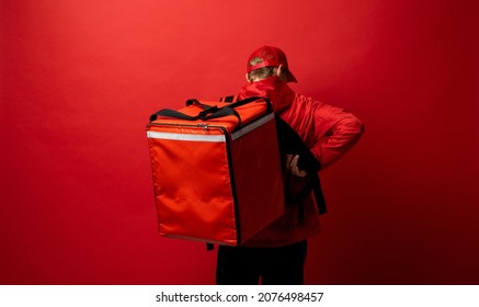 Delivery Man In Red Uniform With A Thermal Backpack Isolated On A White Background. Fast Home Delivery. Online Order. Courier Delivers Groceries Home.