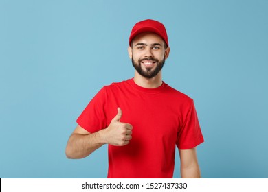 Delivery man in red uniform workwear isolated on blue wall background, studio portrait. Professional male employee in cap t-shirt print working as courier dealer. Service concept. Mock up copy space