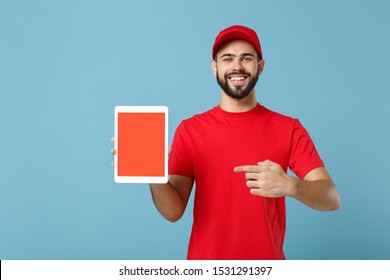 Delivery man in red uniform workwear hold tablet pc isolated on blue background, studio portrait. Professional male employee in cap t-shirt working courier dealer. Service concept. Mock up copy space - Powered by Shutterstock