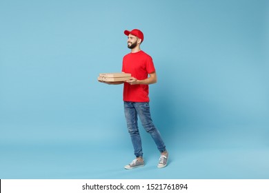 Delivery man in red workwear giving food order pizza boxes isolated on blue background, studio portrait. Professional male employee in cap t-shirt print courier. Service concept. Mock up copy space