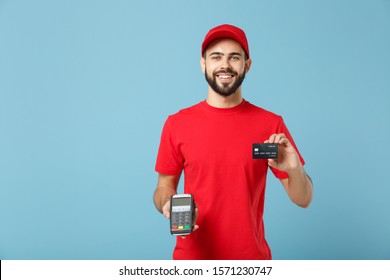 Delivery Man In Red Workwear Hold Bank Payment Terminal To Process Acquire Credit Card Payments Isolated On Blue Background. Employee In Cap T-shirt Working Courier. Service Concept Mockup Copy Space