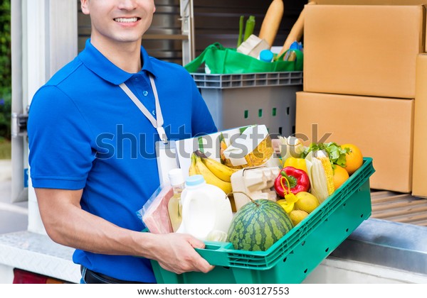 Delivery man taking food\
basket from the car delivering to customer - grocery shopping\
service concept