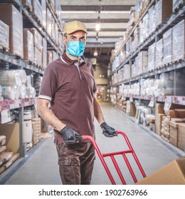 Delivery Man With Uniform And Protective Mask For Covid-19 Inside A Warehouse. Safe Shipping Concept.