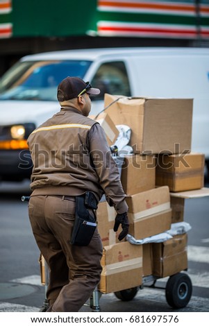 Delivery man walking down New York City street with cart full of packages