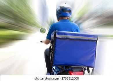 Delivery man wearing blue uniform riding motorcycle and delivery box. Motorbike delivering food express service concept