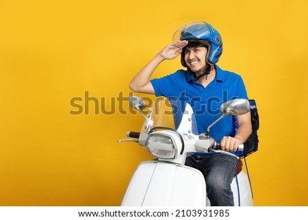 Delivery man wearing blue uniform riding motorcycle and delivery box isolated on yellow background. Motorbike delivering food or parcel express service ストックフォト © 