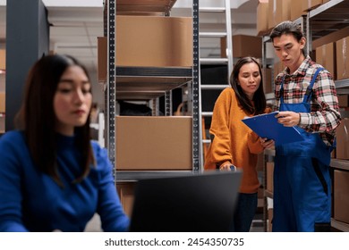 Delivery managers analyzing customer orders list clipboard in ecommerce retail business warehouse. Storehouse asian man and woman employees checking inventory report data in storage room - Powered by Shutterstock