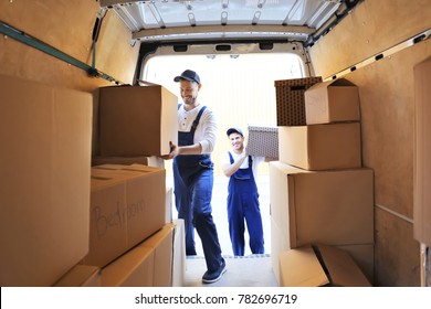 Delivery men unloading moving boxes from car