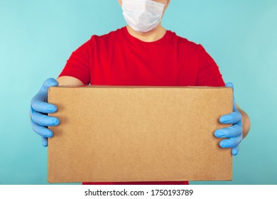 Delivery package concept. Courier in red T-shurt holding box isolated over the blue background. - Shutterstock ID 1750193789