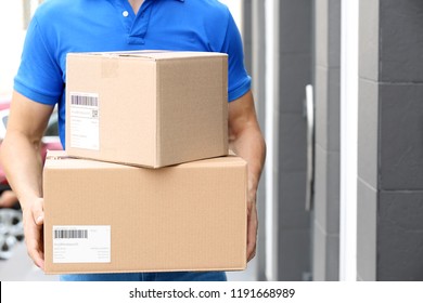 Delivery service courier with parcels in hands outdoors