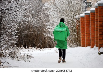 Delivery Service Courier With A Thermos Bag Walking Down The Snow In Winter City. Food Delivery Home