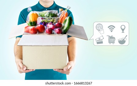 Delivery Service Ingredients Food For Order Online Shopping And Icon Media Symbol. Delivery Man In Green Uniform Hand Holding Paper Box Package For Grocery Express Service Concept.