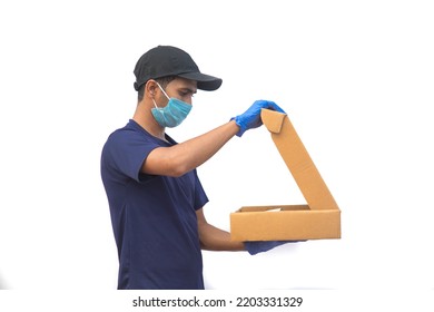 Delivery, Shipping And Postal Service Concept. Delivery Man Opening The Cardboard Box With Safety Precautions Wearing Face Surgical Mask And Hand Gloves To Avoid Contact With The Customer.Isolated 