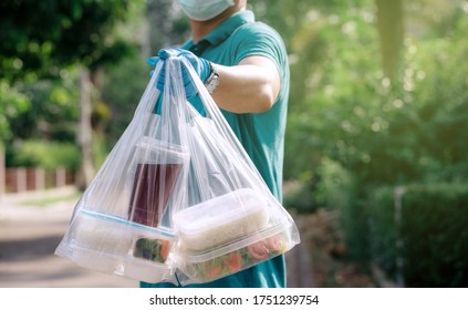 Delivery Staff Of Food Service Delivery Of Ready-to-eat Food To Customers At Home. By Wearing A Mask And Gloves To Prevent The Spread Of The Virus.