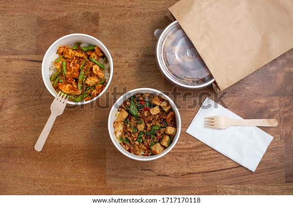 Delivery takeaway asian food. Convenient\
meal in paper food box on wooden table, top\
view