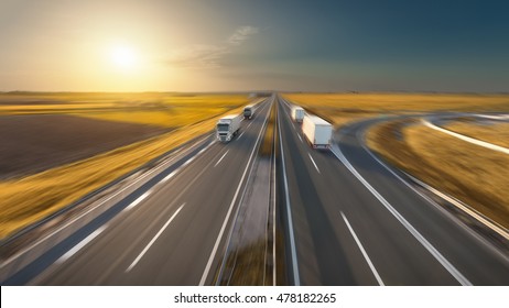 Delivery trucks driving towards the sun. Fast blurred motion image on the freeway in beautiful autumn scenery. Freight scene on the motorway near Belgrade, Serbia.
