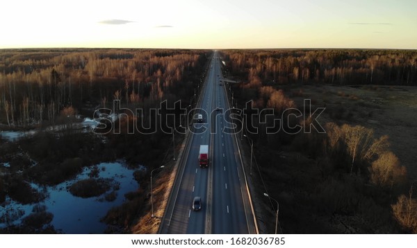 Delivery trucks driving towards the sun. Aerial\
view green fields and\
trucks.