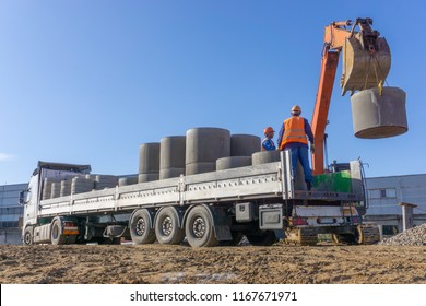 Delivery And Unloading Of Construction Materials By The Excavator To The Construction Site. Concrete Rings And Elements For A Well.