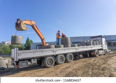 Delivery And Unloading Of Construction Materials By The Excavator To The Construction Site. Concrete Rings And Elements For A Well.