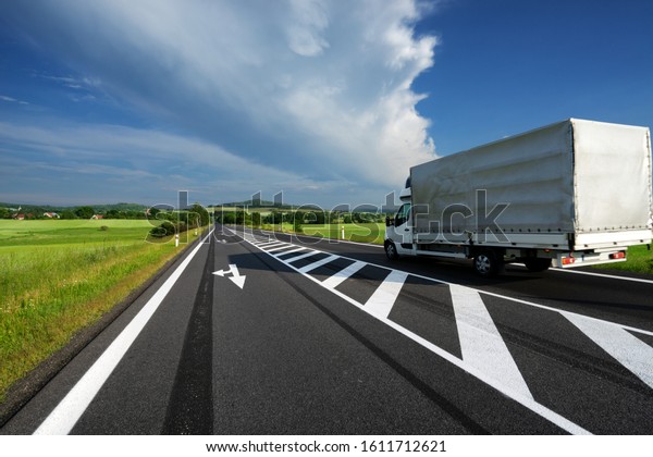 Delivery van transporting goods on asphalt road\
in a rural landscape