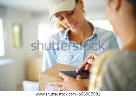 Delivery woman handing package to customer against signature