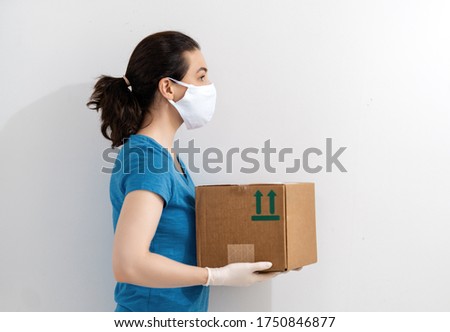 Delivery woman holding cardboard box in medical rubber gloves and mask. Online shopping. Quarantine.