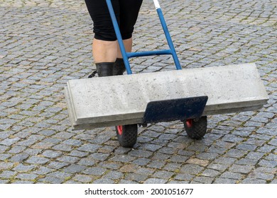 Delivery Woman Pushing A Trolley With Concrete Curb