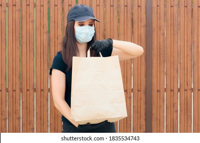 Delivery Woman Wearing Face Mask Holding Package Bag. Fast Food Worker Holding Takeaway Food  In Paper Bag 
