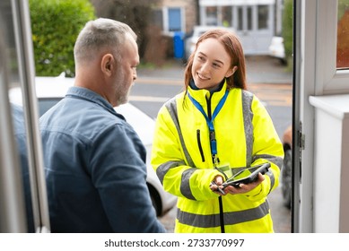 Delivery worker hands over device to customer at the front door in a suburban neighborhood