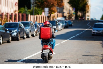 Deliveryboy on scooter with red backpack driving fast to customers, online orders. Courier delivering food on motorbike. Food supplier driving fast on motorcycle. Quick deliver food to customers - Shutterstock ID 1675441576